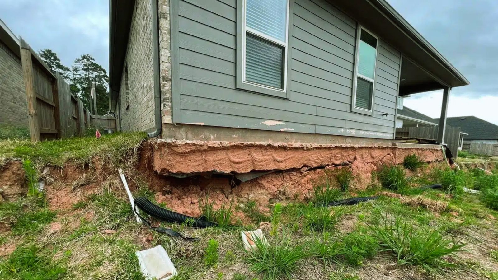  A storm-damaged house with broken windows and a collapsed roof, surrounded by debris and fallen branches.