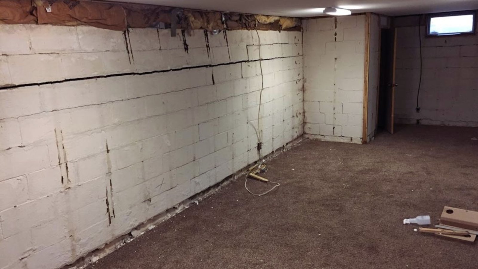 A basement with a partially repaired wall, showing tools and materials used for the renovation process.