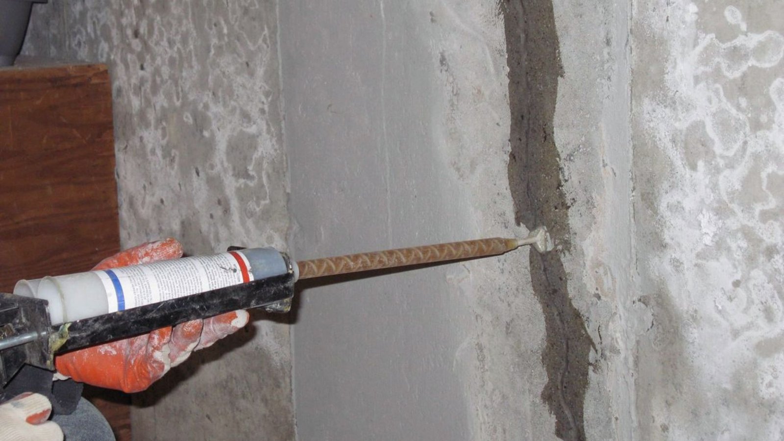 A man repairs a wall using a tool, focused on fixing the surface with precision and care.