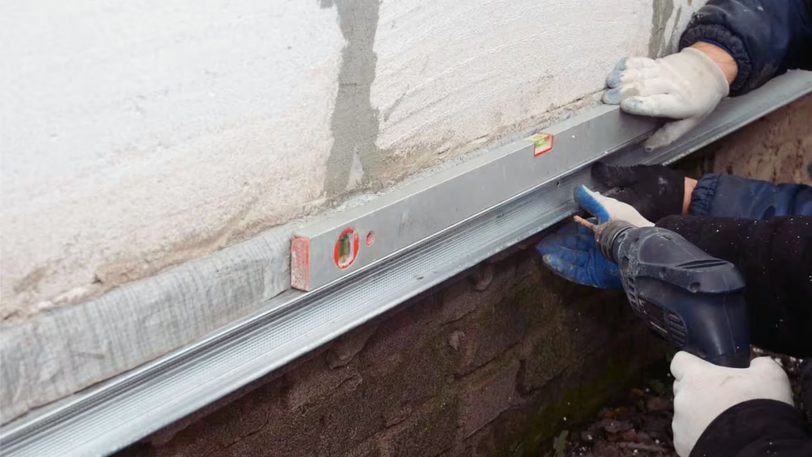 A man drills into a surface to install a metal rail securely in place.
